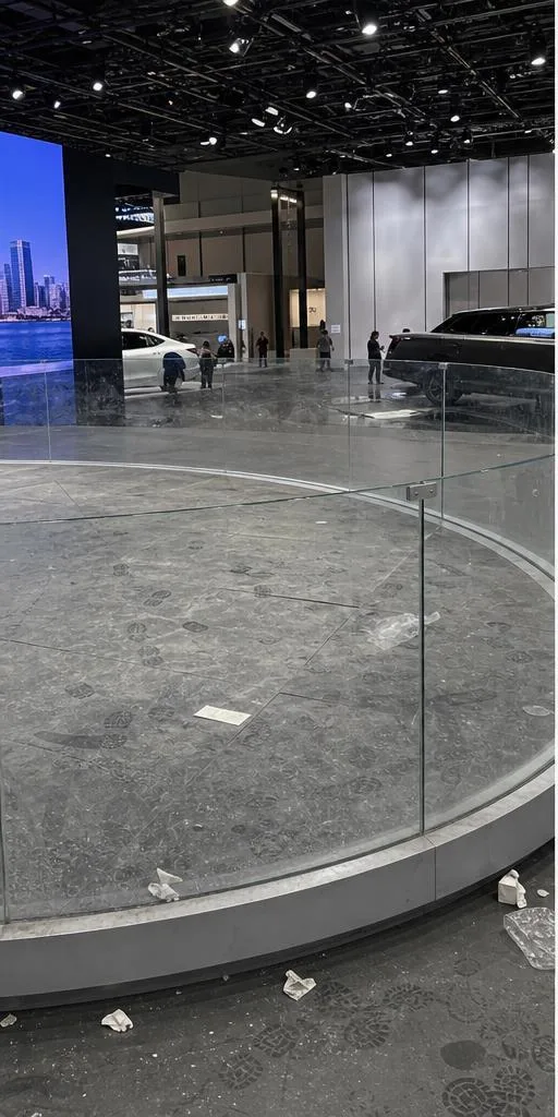 車展展台地面佈滿鞋印塵埃、玻璃圍欄留有指模